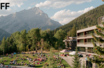 People sitting on a grassy field in Banff, with the mountains in the background. Banff Centre logo in upper left corner.