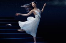 Ballerina in a white dress dancing on stage under a starry sky, evoking a dreamlike, storybook atmosphere.