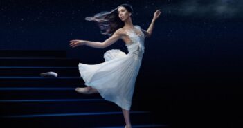 Une ballerine en robe blanche qui danse sur scène sous un ciel étoilé, créant une atmosphère onirique digne d'un conte de fées.